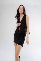 Chaleco negro de estilo boho, confeccionado en semigamuza con detalles de tejido de punto en el frente y la espalda. Presenta un diseño sin mangas con flecos en el ruedo, aportando movimiento y textura a la prenda.