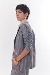 Blazer de lino color crudo con rayas verticales finas en color dorado, de corte recto, con solapas y cierre con un botón.