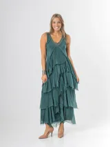 Vestido largo negro de seda italiana con diseño sin mangas de bretel ancho y escote en V profundo con detalles de paillettes plateados. Presenta múltiples capas con volados y bordes deshilachados que aportan movimiento y una caída fluida.