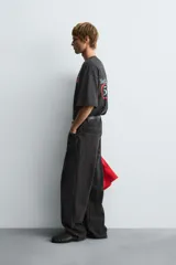 Camiseta negra con efecto lavado, corte boxy fit, cuello redondo y manga corta. Presenta un estampado frontal con texto en tonos turquesa, rojo y blanco que dice "Tuesday 600 Marathon Day Hyde Park".