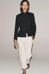 Blazer negro de mezcla de algodón, con cuello subido y manga larga. Cuenta con falsos bolsillos de vivo en el delantero y cierre frontal con alamares a tono.