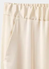 Pantalón de tiro medio confeccionado en tejido satinado de corte recto y largo, con bolsillos laterales, aberturas en el bajo y detalle de costuras.