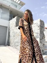 Vestido midi con estampado animal print de leopardo en tonos beige y marrón, con cierre frontal de botones y detalles en color negro en el cuello, mangas y borde central.