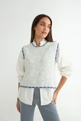Chaleco de punto gris melange con detalles de costuras en color azul en el cuello, sisas y ruedo.