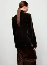 Blazer de corte recto confeccionado en tejido de terciopelo color marrón oscuro. Presenta cuello con solapas de muesca, cierre frontal con un botón, mangas largas con puños abotonados y dos bolsillos laterales con solapa. Incluye forro interior.
