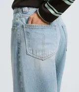 Pantalón baggy de jean en color azul claro, con cintura mediana, corte amplio y recto. Cuenta con bolsillos funcionales, trabillas para cinturón y cierre frontal con botón y cremallera.