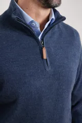 Sweater verde oliva de tejido acrílico con textura similar al cashmere, corte clásico, cuello alto con cierre metálico y tirador de cuerina ecológica.