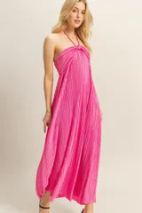 Vestido largo de corte fluido con diseño plisado en toda la prenda. Presenta escote halter con detalle de nudo en el centro del pecho y espalda descubierta.