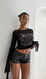 Blusa de mesh negra con transparencias, manga larga y estampa frontal en tipografía vintage color blanco.