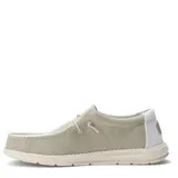 Zapatos tipo slip-on de tela color beige, con diseño de costuras expuestas, cordones elásticos decorativos y suela de goma blanca.