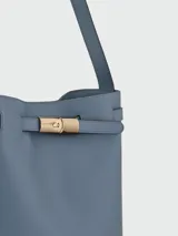 Bolso tipo shopping bag de cuero azul, con diseño estructurado, asa de hombro fija y detalle de cierre metálico dorado en la parte superior.