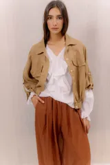 Campera liviana de lino color tostado, con cierre frontal de botones, bolsillos ojal en el pecho y mangas anchas con presilla y botón en los puños.