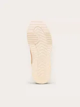 Championes Sorel modelo Ona Ave T-Toe, color beige con detalles en gamuza y cuero. Presenta suela de plataforma con diseño estriado y detalle metálico dorado en el talón.