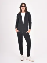 Monoprenda de estilo deportivo color negro, con cierre frontal parcial, mangas largas y cintura elástica con cordón ajustable. Presenta un diseño de pantalón tipo jogger con puños en los tobillos.