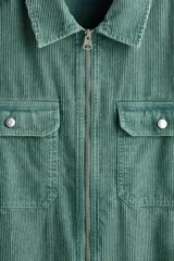 Sobrecamisa de pana de algodón color verde, con cuello clásico, cierre frontal de cremallera, mangas largas con puños abotonados y bolsillos superiores con solapa y botón.