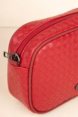 Cartera tipo bandolera de diseño trenzado, con correa ajustable y desmontable de cinta técnica. Cuenta con cierre superior y detalle de aplique metálico en el frente.