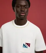 Remera de algodón color crudo, con cuello redondo y manga corta. Presenta un bolsillo en el pecho con estampa náutica y lettering "M.R.F.".