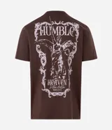 Remera de algodón color marrón con cuello redondo y mangas cortas. Presenta un diseño gráfico de estilo barroco con una figura alada y la inscripción 'Humble' en la espalda.