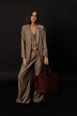 Pantalón de vestir de corte amplio y tiro alto, confeccionado en tela de casimir color tostado. Presenta pinzas frontales, cierre con botón de carey y detalle de pespunte negro en el ojal.