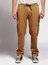 Pantalon tipo jogger cargo color tostado, con cintura elástica ajustable mediante cordón, bolsillos laterales con solapa y puños elásticos en los tobillos.