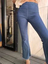 Calza de jean azul elastizada, tiro alto, corte ajustado y terminación desflecada en el ruedo.