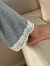 Pijama de algodón gris con textura acanalada, compuesto por una remera de escote en V decorado con puntilla y un pantalón recto con elástico y lazo en la cintura.