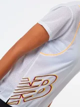 Remera deportiva blanca para mujer, de manga corta, con cuello redondo en tono amarillo y un gran estampado del logo de New Balance en el lateral inferior.