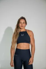Top deportivo de cuello alto con tiras finas en la espalda, confeccionado en tela técnica de poliamida y elastano. Presenta un pequeño logo bordado en el centro del pecho.