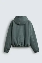 Cazadora negra de algodón con efecto lavado, corte relajado y capucha ajustable. Presenta cierre frontal de cremallera, bolsillos frontales tipo canguro y elásticos en puños y bajo.