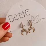Aros colgantes dorados con forma de medialuna y pequeños brillantes incrustados.