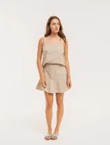 Falda corta color beige con rayas verticales blancas, corte evasé y volado en el ruedo.