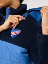 Parka de abrigo Umbro del Club Nacional de Football, con diseño bicolor que combina tejido polar blanco en la parte superior y tejido acolchado azul marino en la parte inferior. Cuenta con cierre frontal completo, cuello alto y bolsillos laterales.