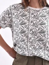 Remera de manga corta color beige con estampado de bananas en tonos amarillo, naranja y rosado.