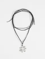 Collar largo de cordón negro con dije metálico plateado en forma de contorno de flor.