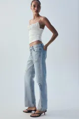 Jeans rectos de tiro medio en denim azul con efecto deslavado. Presentan diseño de cinco bolsillos, cierre frontal con botones metálicos y dobladillo vuelto en el bajo.