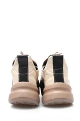 Championes deportivos acordonados de cuero, con diseño combinado en tonos beige, marrón y negro. Presenta suela de plataforma en color tostado y detalles metálicos en los ojales de los cordones.
