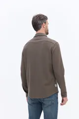 Camisa de manga larga color azul marino, confeccionada en algodón con textura, cuenta con un bolsillo frontal y cierre frontal con botones.