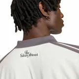 Buzo adidas de manga larga estilo polo, perteneciente a la colección Mercedes F1 Team AMG-Petronas. Es de color blanco con detalles en gris oscuro en el cuello, puños y franjas en las mangas, e incluye el logo de adidas y el escudo del equipo en el pecho.