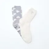 Pack de dos pares de medias de tejido suave y afelpado. Un par es de color gris con estampado de corazones blancos y antideslizante en la planta, y el otro par es de color blanco liso con un pequeño corazón bordado.