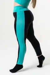 Calza deportiva de tiro alto con cintura elástica reforzada. Presenta un diseño bicolor que combina paneles laterales y faja con estampado animal print en tonos coral y turquesa sobre una base negra.