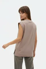 Musculosa color crudo con estampado frontal de paisaje montañoso y texto "EXPLORING Outlands", corte holgado y aberturas laterales en el ruedo.