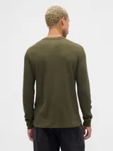 Remera de manga larga confeccionada en tejido tipo waffle, color verde oliva. Presenta cuello redondo y el logo de la marca bordado en el centro del pecho en un tono similar a la prenda.