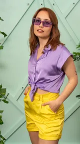 Camisa de satén color lila, con cuello clásico, cierre frontal con botones y diseño corto anudado en la cintura.