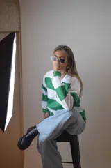 Sweater blanco con rayas horizontales verdes, de corte holgado y mangas largas.