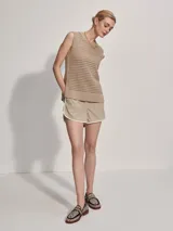 Musculosa de punto color beige con diseño calado y aberturas laterales.