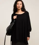 Suéter de tricot color negro con escote canoa, mangas murciélago y puños ajustados.