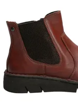 Botín tipo Chelsea de cuero color marrón, con paneles laterales elásticos en color oscuro y suela de goma dentada flexible.