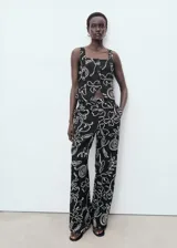 Top sin mangas de tejido mezcla de lino, con cuello escotado y cierre frontal de tres botones. Presenta un diseño entallado con estampado floral en contraste y dos bolsillos de ribete frontales.