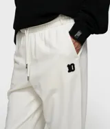Pantalón deportivo de corte holgado, color blanco, con cintura elástica ajustable con cordón, bolsillos laterales y puños elásticos en los tobillos.