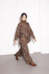 Camisa marrón con estampado abstracto en negro y beige, cuello alto con detalle de piel sintética marrón, manga larga y corte holgado.